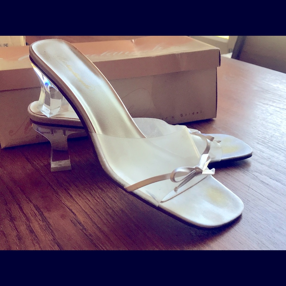 White satin bow over clear plastic. Heels are clear- looks like a glass slipper!